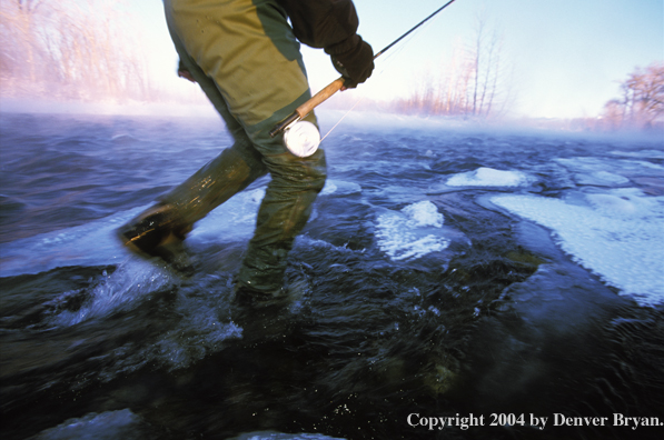 Flyfisherman wading in an icy stream.