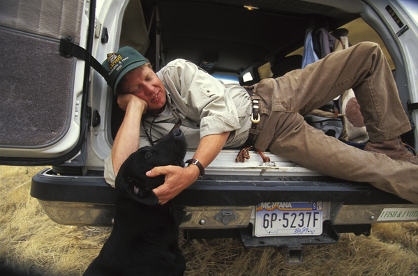 Upland bird hunter taking a break with black Labrador Retriever.