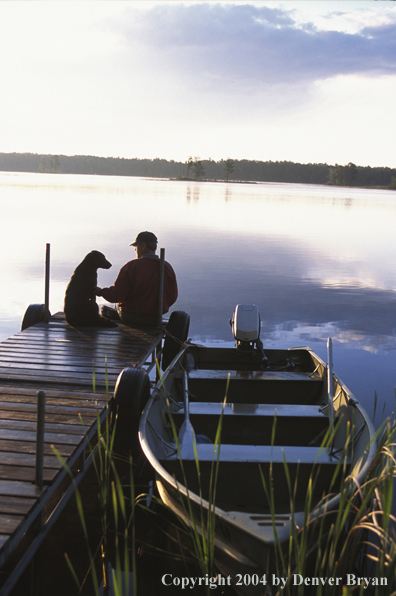 Spincast fisherman with dog on boat dock.