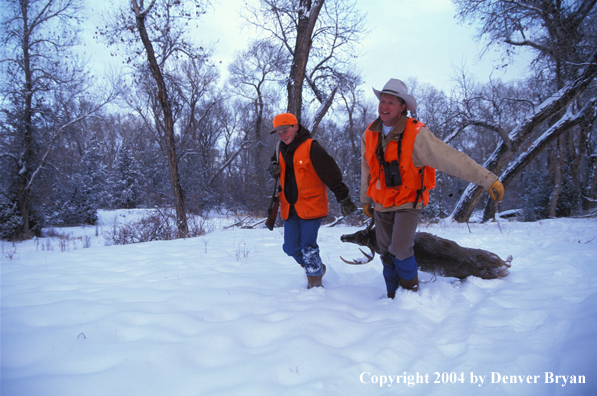 Father and son dragging white-tailed deer.