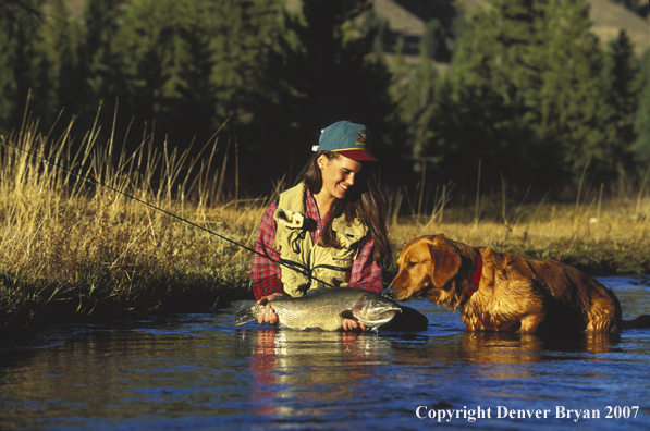 Woman flyfisher with catch and yellow Lab.