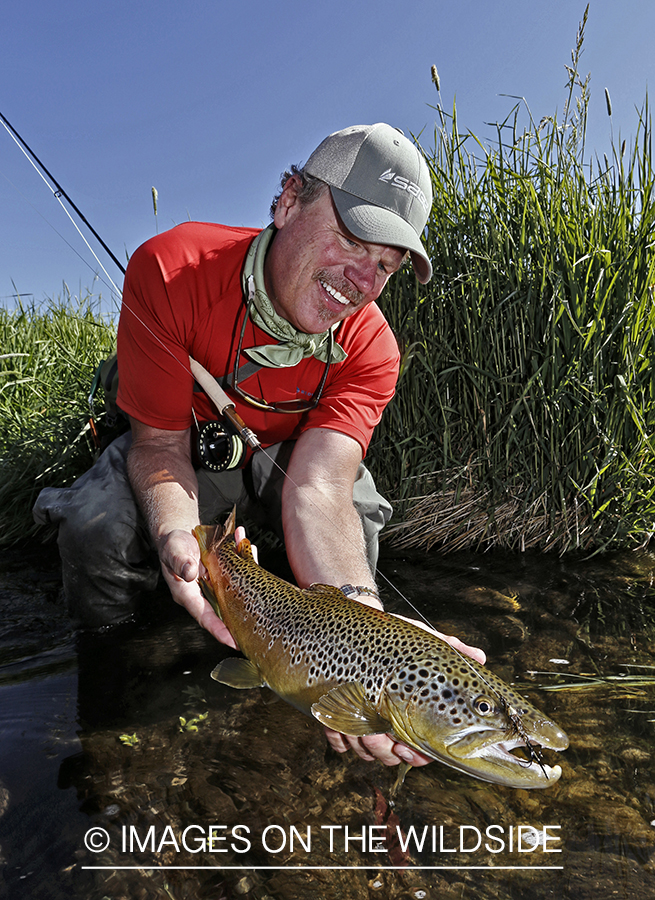 Flyfisherman with brown trout. (HDR)