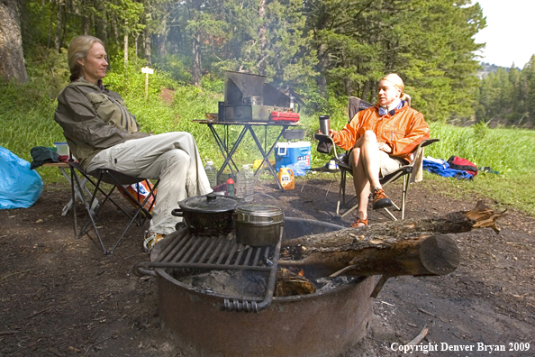 Ladies sitting around campfire.