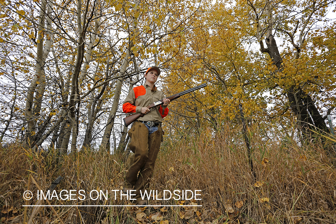 Woman in woodland hunting pheasant.