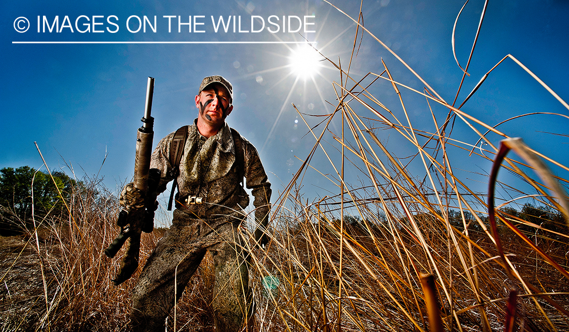 Hunter with AR15 rifle in field. 