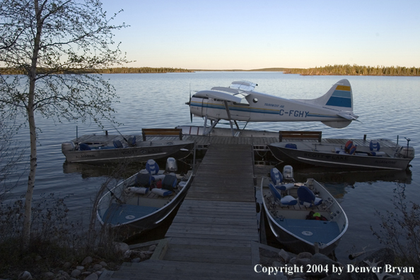 Float plane and fishing boats tied up to the dock at dusk.  Saskatchewan.