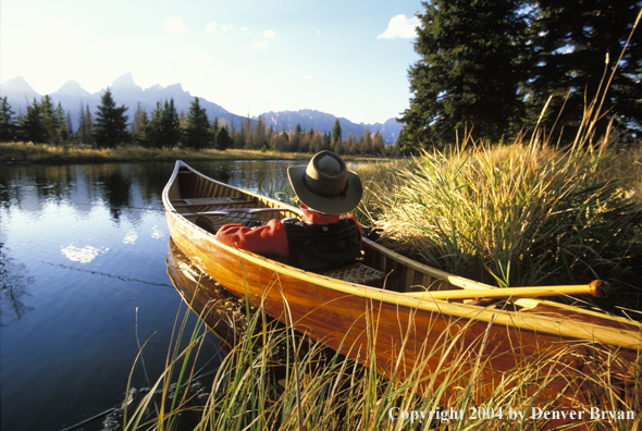 Flyfisherman in wooden cedar canoe.  Teton mountains in background.