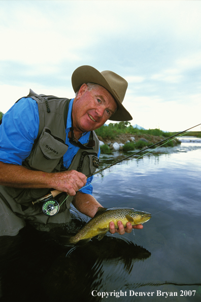 Flyfisherman holding brown trout.