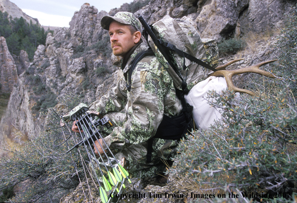 Bowhunter with mule deer horns on back.