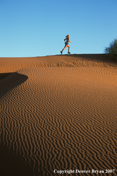 Woman running on sand dunes in Sossusvlei park, Namibia. Africa