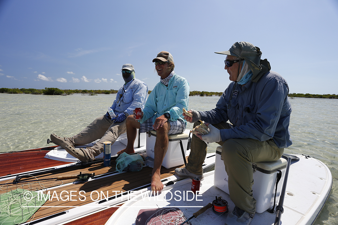 Flyfishermen having lunch on stand up paddle boards.