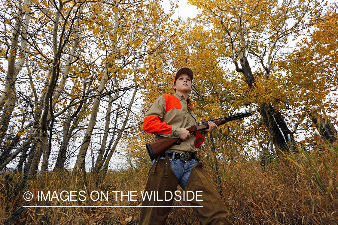 Woman in woodland hunting pheasant.