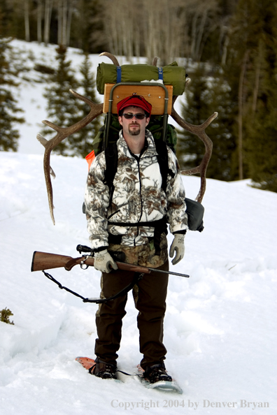 Big game hunter packing elk rack out on snowshoes.