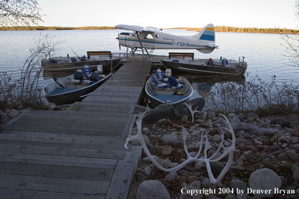 Float plane and fishing boats tied up to the dock at dusk.  Saskatchewan.