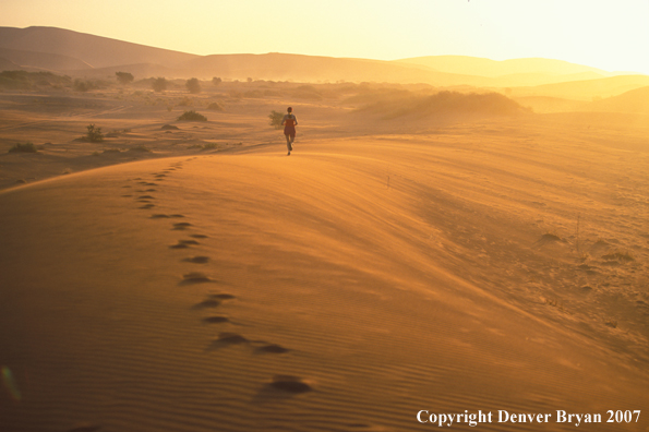 Woman running on sand dunes in Sossusvlei park, Namibia. Africa