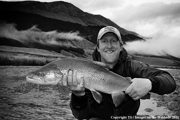 Fisherman with brown trout on the Oreti River, New Zealand. 