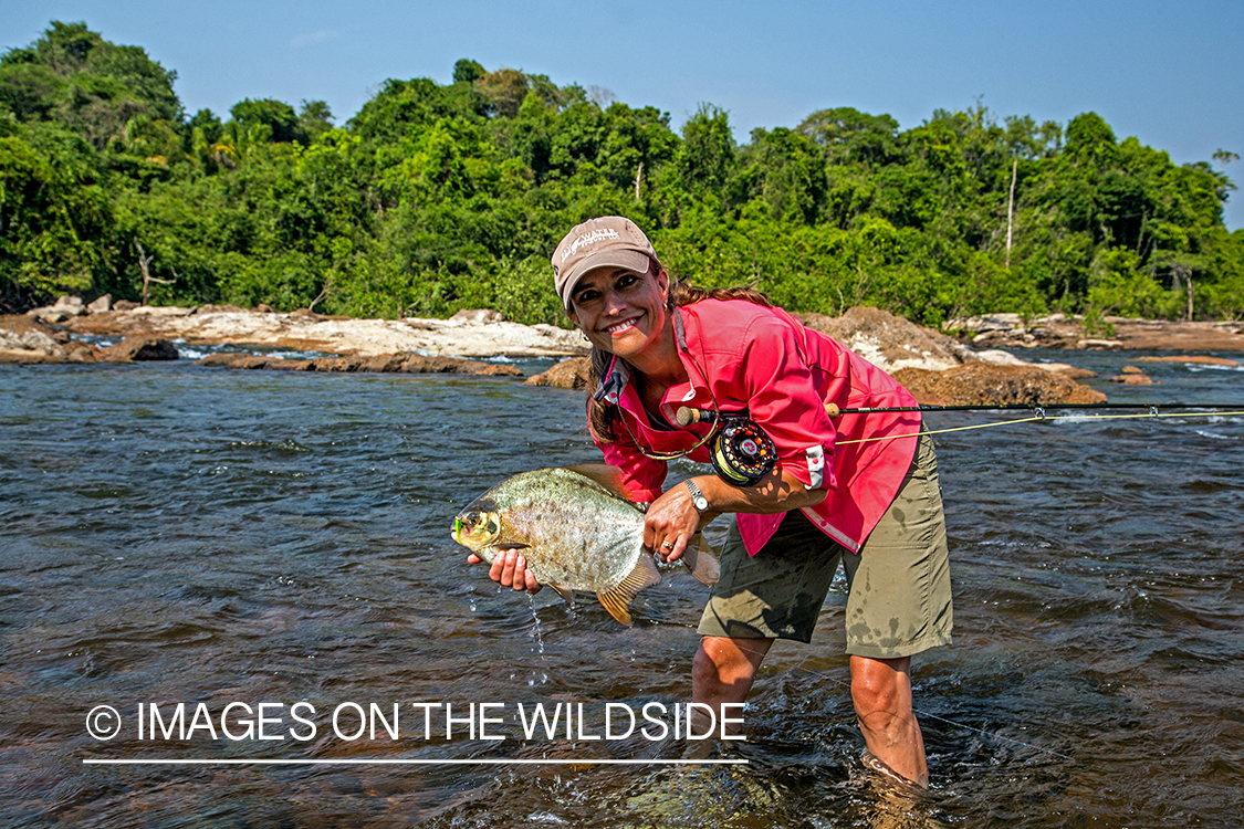 Woman flyfisherman with piranha in river in Kendjam region, Brazil.