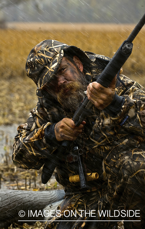 Waterfowl hunter camouflaged in field.