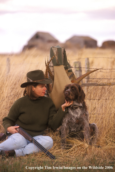 Woman upland game bird hunter and German Wirehair Pointer with bagged pheasants.  