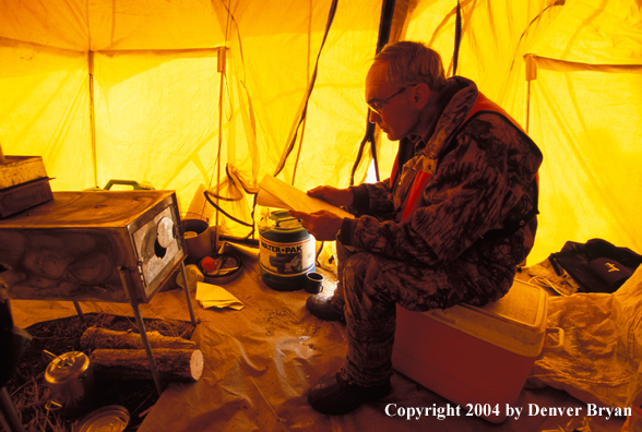 Big game hunter in tent reading map.