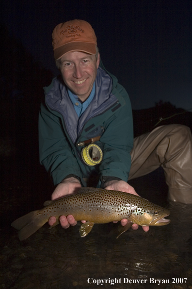 Flyfisherman with brown trout at dusk.