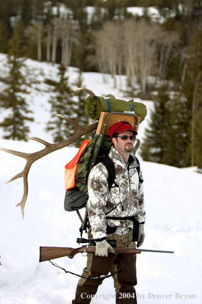 Big game hunter packing elk rack out on snowshoes.