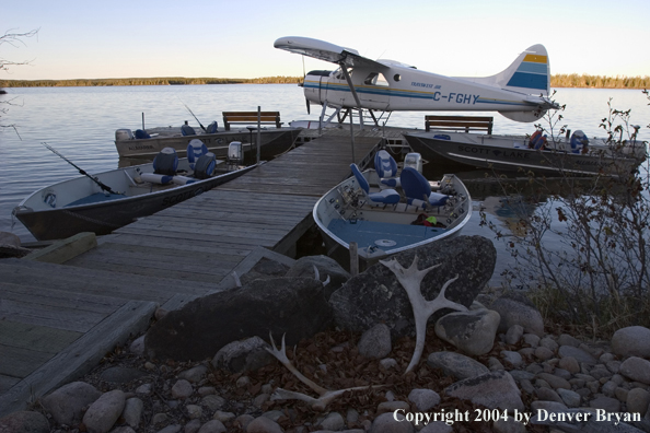 Float plane and fishing boats tied up to the dock at dusk.  Saskatchewan.