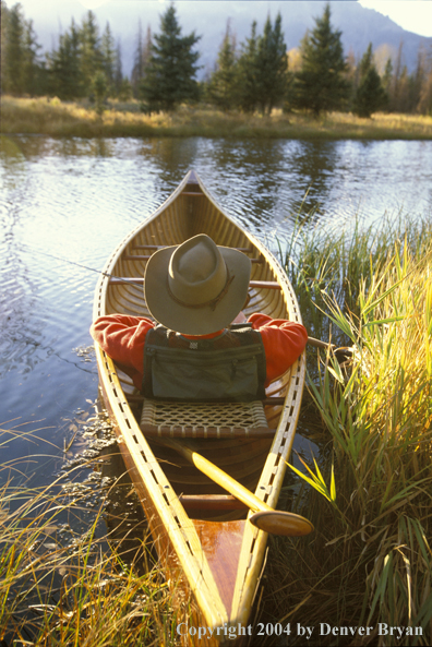 Flyfisherman in wooden cedar canoe.  Teton mountains in background.