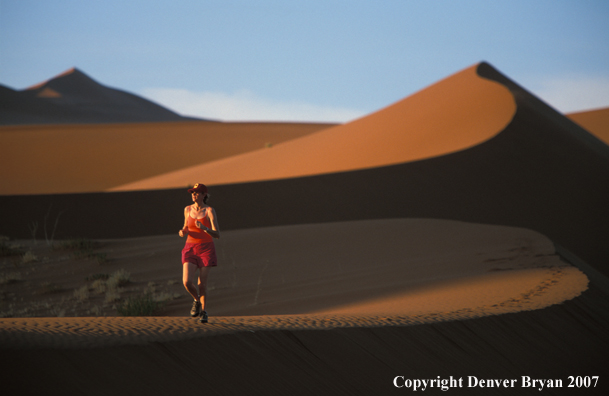 Woman running on sand dunes in Sossusvlei park, Namibia. Africa