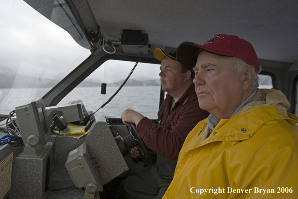 Boat captain at the helm with fisherman looking for fish.  