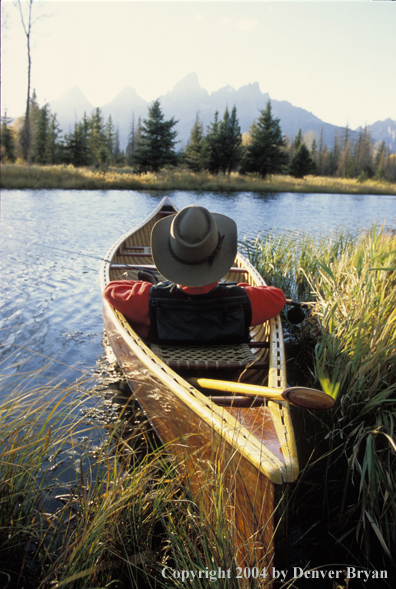 Flyfisherman in wooden cedar canoe.  Teton mountains in background.