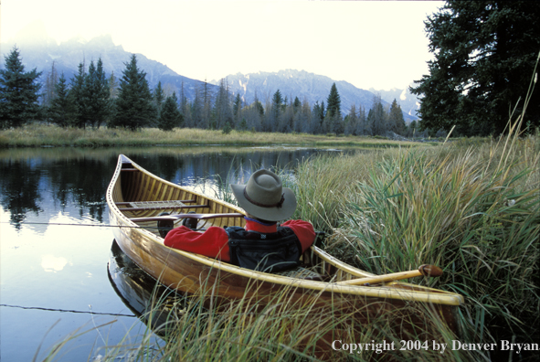 Flyfisherman in wooden cedar canoe.  Teton mountains in background.