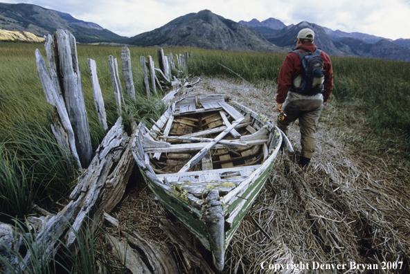 Angler walks by a very old canoe