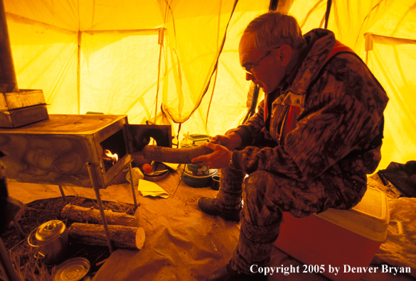 Big game hunter in tent reading map.