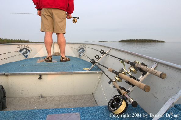 Flyfisherman looking out over lake from bow of boat.