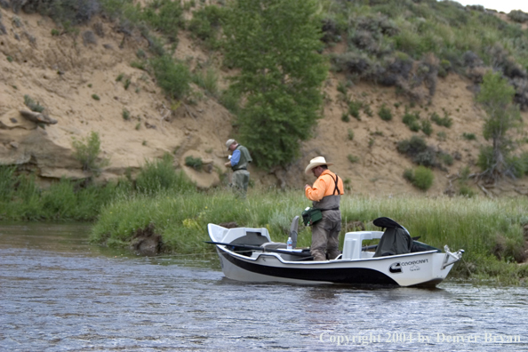 Flyfisherman in drift boat rigging up to fish.