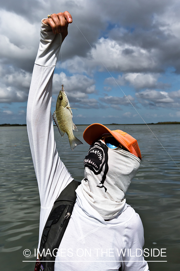 Flyfishing woman pretending to eat small fish on line.