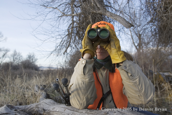 Woman big game hunter glassing for game.