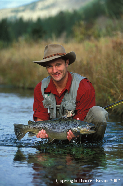 Flyfisherman holding brown trout.