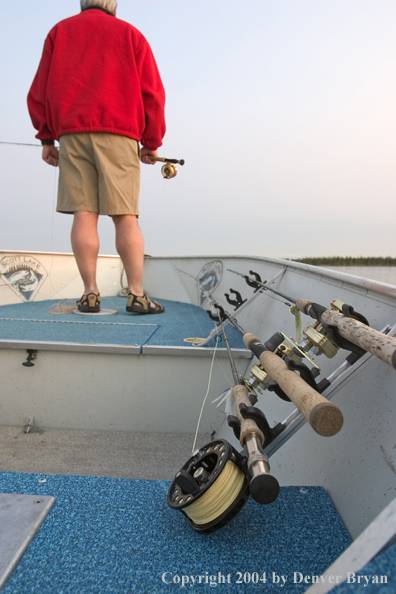 Flyfisherman looking out over lake from bow of boat.