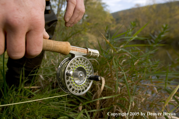 Close-up of flyfisherman holding reel on Pennsylvania spring creek.