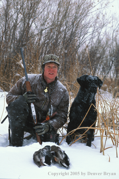 Waterfowl hunter with black Lab and ducks. 