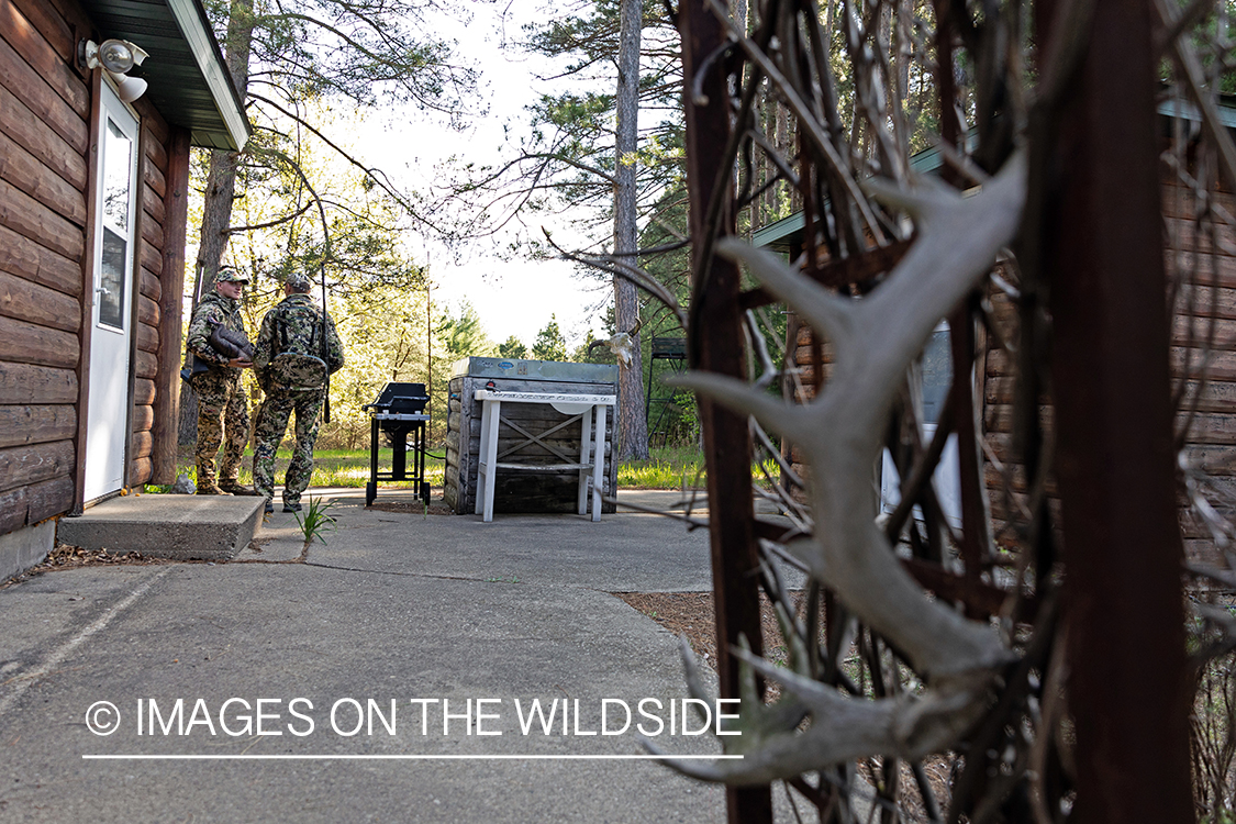 Hunters talking outside cabin.