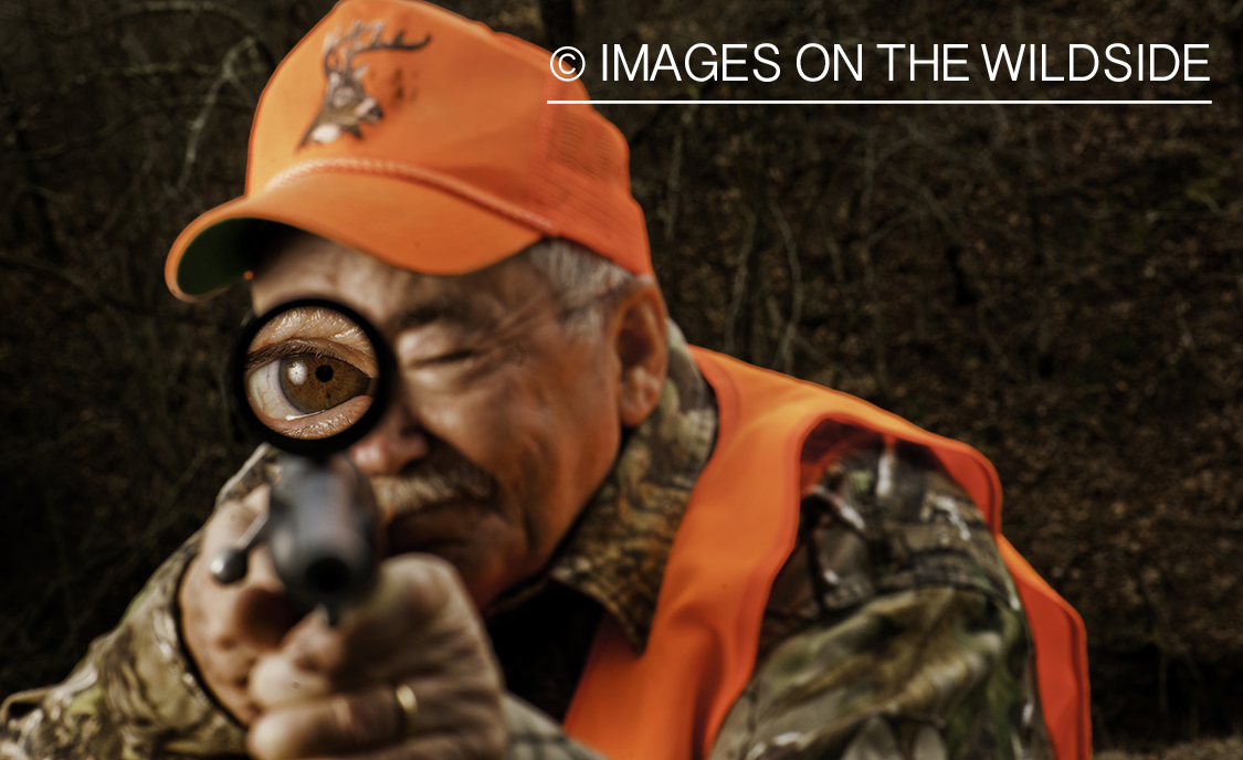 Hunter aiming through rifle scope.