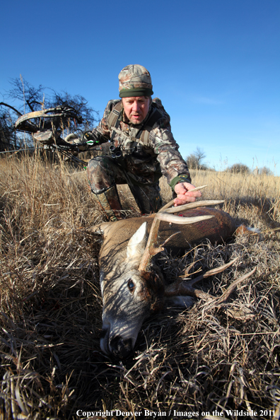 Bowhunter with bagged buck. 