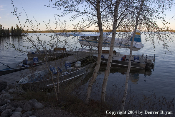 Float plane and fishing boats tied up to the dock at dusk.  Saskatchewan.