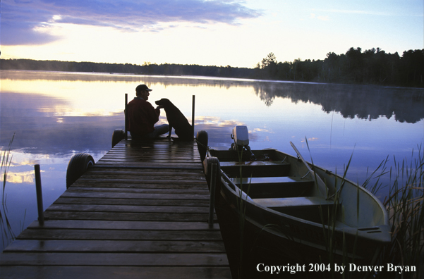 Spincast fisherman on dock with dog