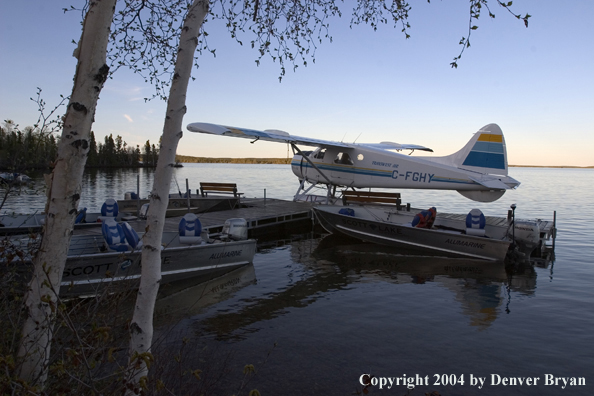 Float plane and fishing boats tied up to the dock at dusk.  Saskatchewan.