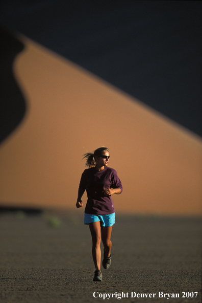 Woman running on sand dunes in Sossusvlei park, Namibia. Africa