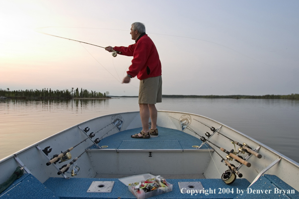 Flyfisherman fishing lake from bow of boat.